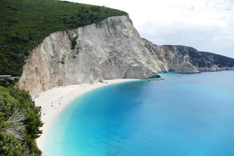 Vista panorâmica da deslumbrante Egremni Beach em Lefkada, Grécia, com sua longa faixa de areia branca, falésias imponentes e águas azul-turquesa cristalinas.