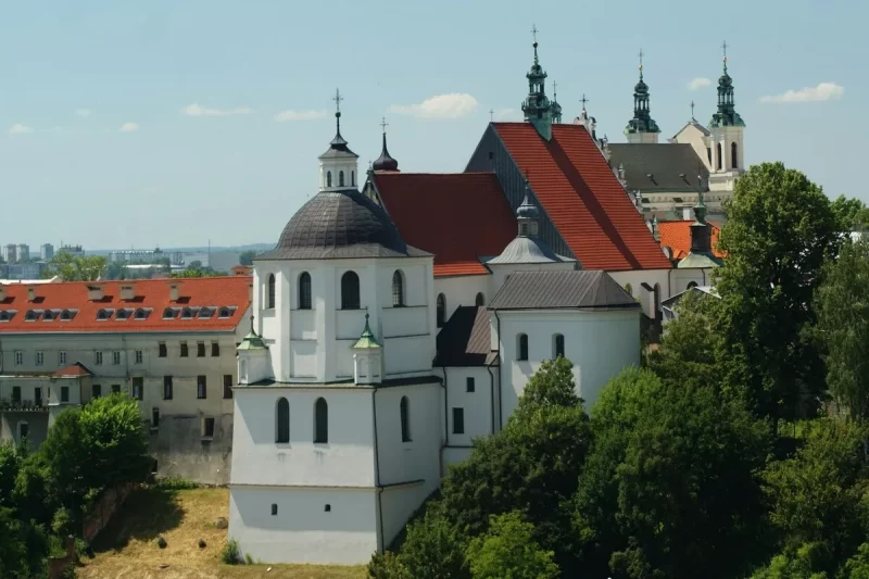 Um conjunto arquitetônico de igrejas e monastérios de estilo barroco e renascentista com telhados vermelhos e cúpulas escuras, característico da paisagem histórica da Europa Central.
