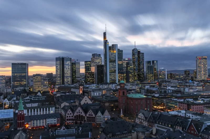 Skyline de Frankfurt, Alemanha, ao anoitecer, mostrando a combinação de arranha-céus modernos e a cidade antiga iluminada.