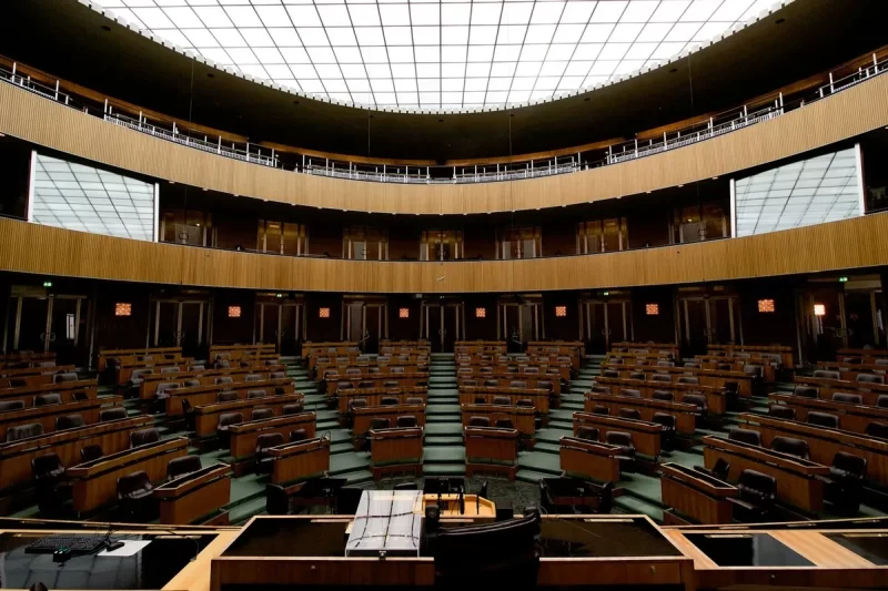Interior da câmara do Parlamento Austríaco em Viena, com assentos em semi-círculo e teto de vidro.