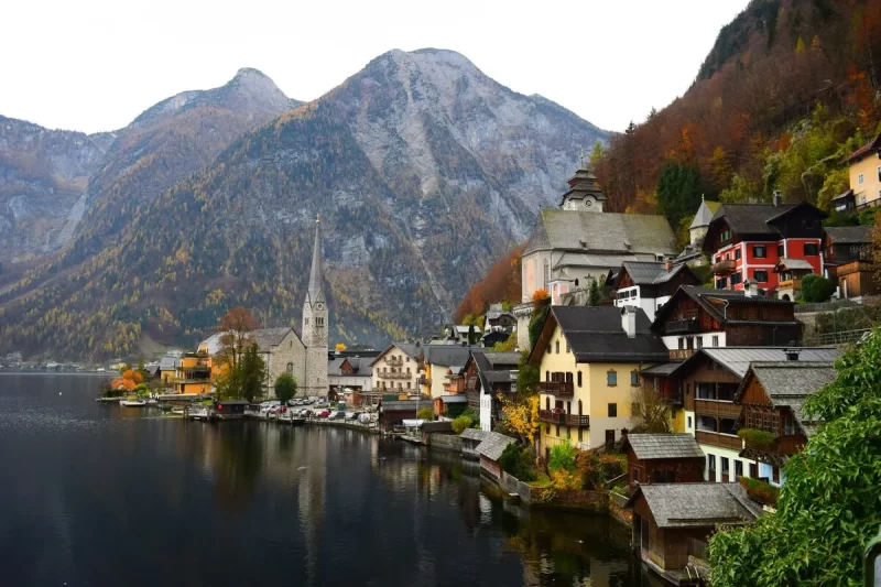 Vista panorâmica da pitoresca vila de Hallstatt, na Áustria, com casas coloridas às margens do lago e montanhas ao fundo, destacando a necessidade de seguro viagem na Europa para destinos tão belos.