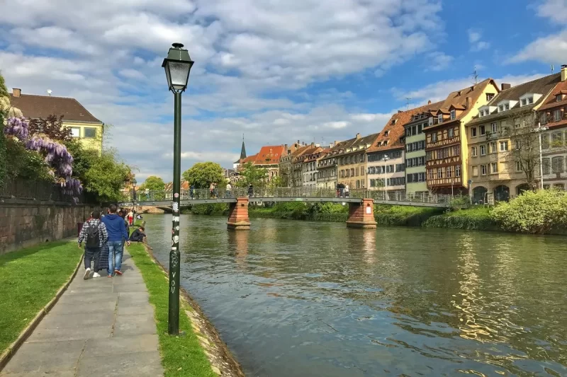 Vista de Estrasburgo, na França, com o rio, ponte e casas históricas.