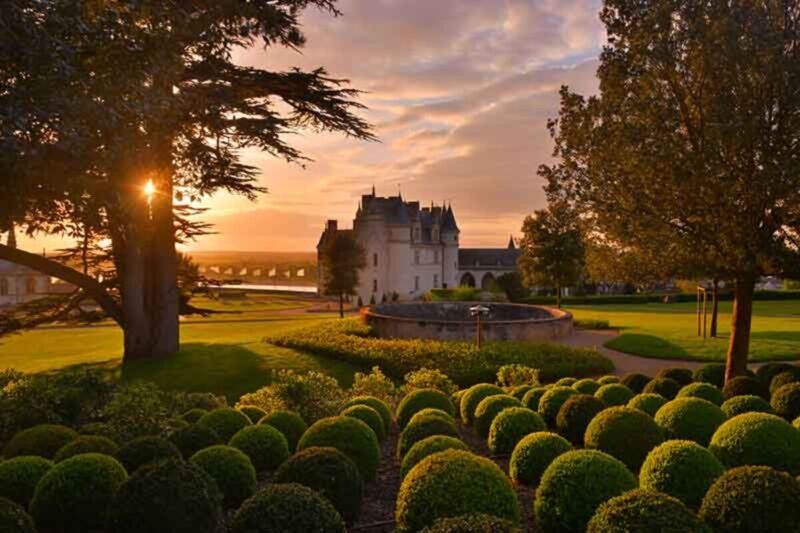 Castelo do Vale do Loire ao pôr do sol, com jardins bem cuidados e luz dourada.
