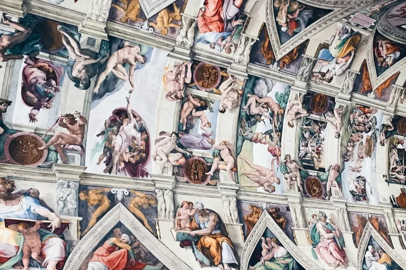 Um close-up dos famosos frescos de Michelangelo no teto da Capela Sistina, uma das maiores obras de arte do Vaticano. A imagem mostra as cenas bíblicas e as figuras nuas que compõem a obra-prima.