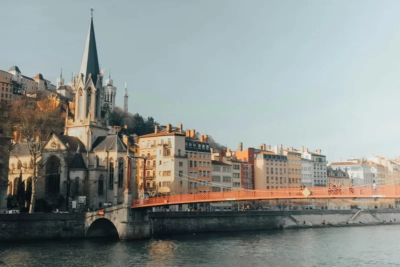 Imagem da Ponte Saint-Georges sobre o Rio Saône em Lyon, com a Igreja Saint-Georges e prédios históricos ao fundo.